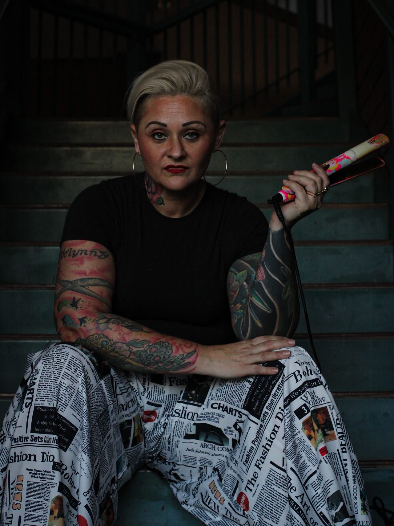 Stephanie Wood, owner and stylist at The Rebel Room, holding a flat iron